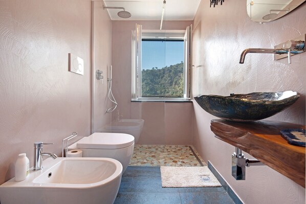 A bathroom with a bathtub, a sink, a toilet, and a window with a view of a forest. - Apartment 'Ca' Dû Massunin' with Sea View, Wi-Fi and Air Conditioning (Recco)