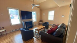 A living room with a fireplace, a television, a ceiling fan, and a sofa.
