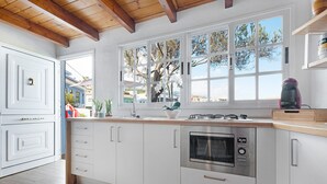 A modern kitchen with white cabinets, a stainless steel oven, a window with a view of trees, and a wooden ceiling. - Holiday Home 'Casa Evarista' with Sea View, Private Terrace and Wi-Fi (Icod de los Vinos)