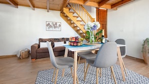 A dining area with a wooden staircase, a sofa, and a table with chairs. - Holiday Home 'Casa Evarista' with Sea View, Private Terrace and Wi-Fi (Icod de los Vinos)