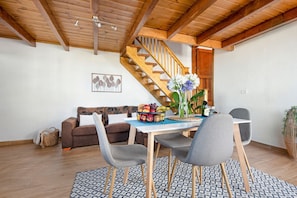 Ein Essbereich mit einer Holztreppe, einer Couch und einem Tisch mit Stühlen.
