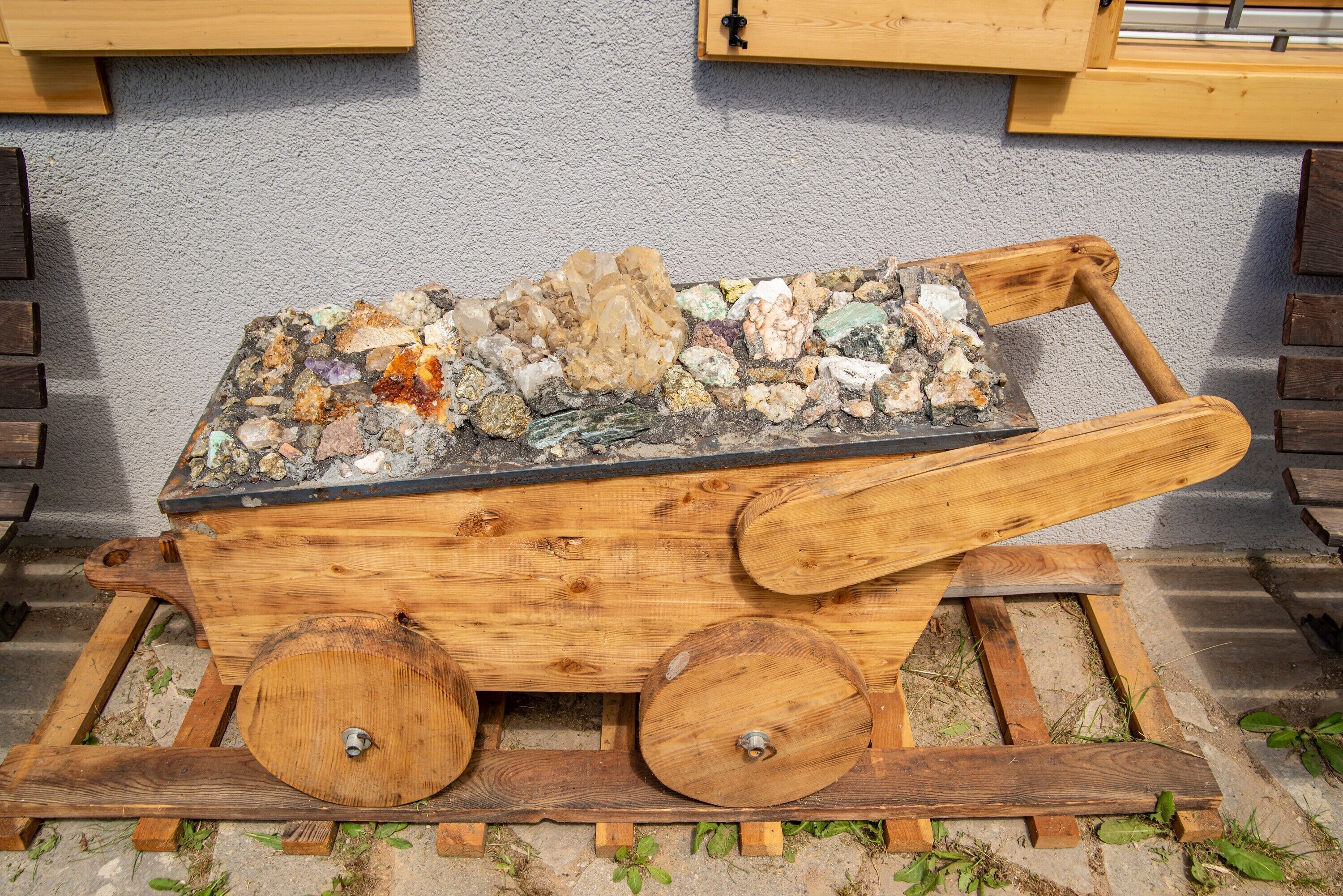 Una carrossa de fusta amb una superfície de pedra, col·locada sobre una base de formigó amb una paret gris al fons.