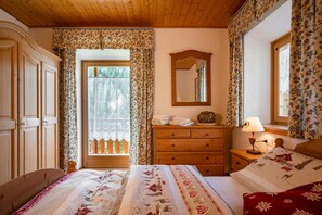 A bedroom with a wooden bed, a dresser, a mirror, and a window with floral curtains.