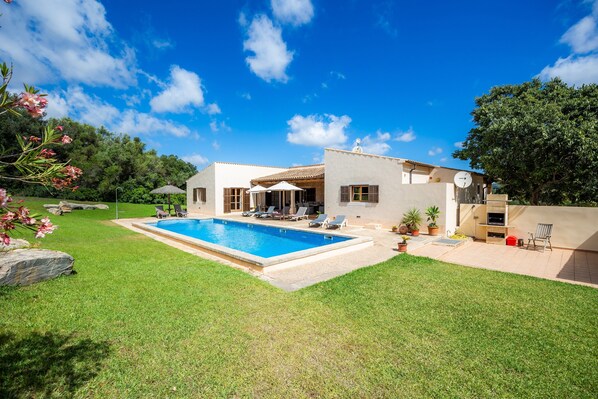 A house with a swimming pool, outdoor seating, and a garden.