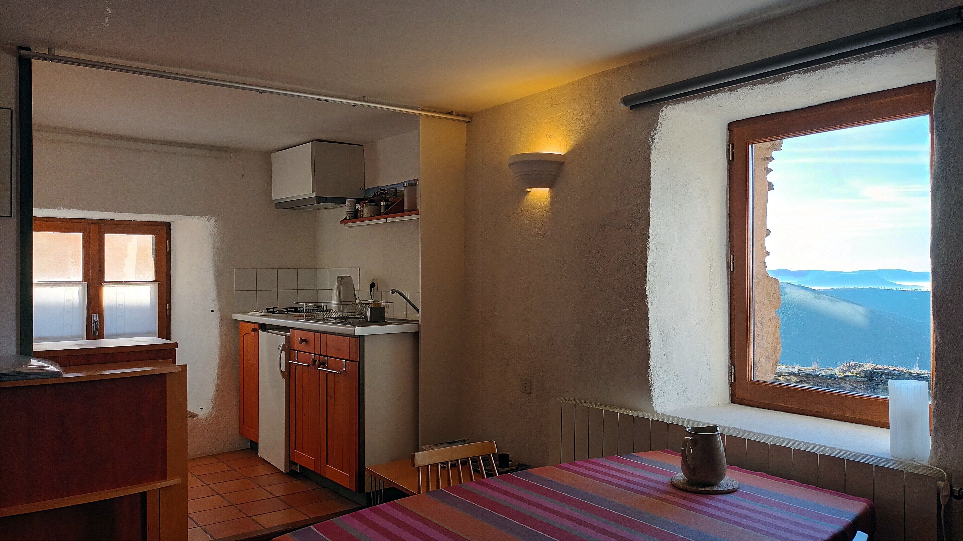 A compact kitchen with a window, a table, and a view of the outdoors.
