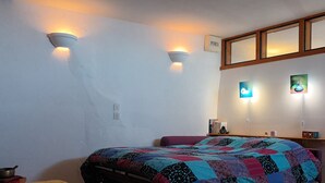 Un dormitorio con cama, dos luces empotradas, una estantería con libros y un cuadro enmarcado.