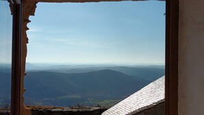 Vista a través de una ventana de un paisaje montañoso con colinas lejanas y cielo despejado.