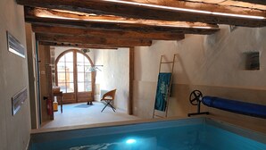 Una piscina con techo de madera, una silla y una escalera.