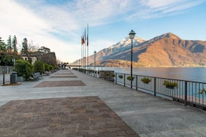A waterfront promenade with a paved walkway, benches, and lampposts.