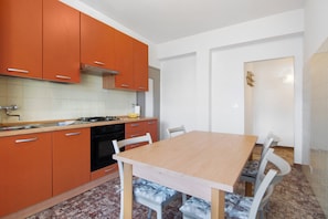 A kitchen with orange cabinets, a wooden table, and white chairs.