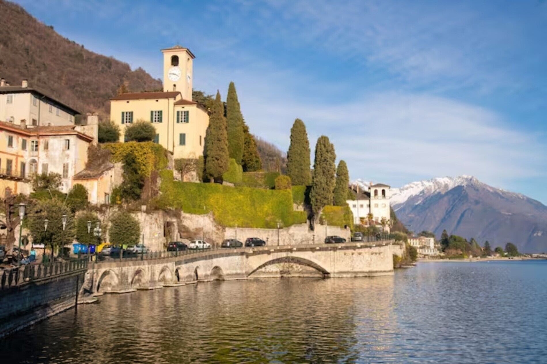 A riverside town with a bridge, buildings, and a mountain backdrop.