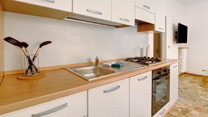 Une cuisine moderne dotée d’un évier en acier inoxydable, d’une cuisinière à gaz et d’armoires blanches.