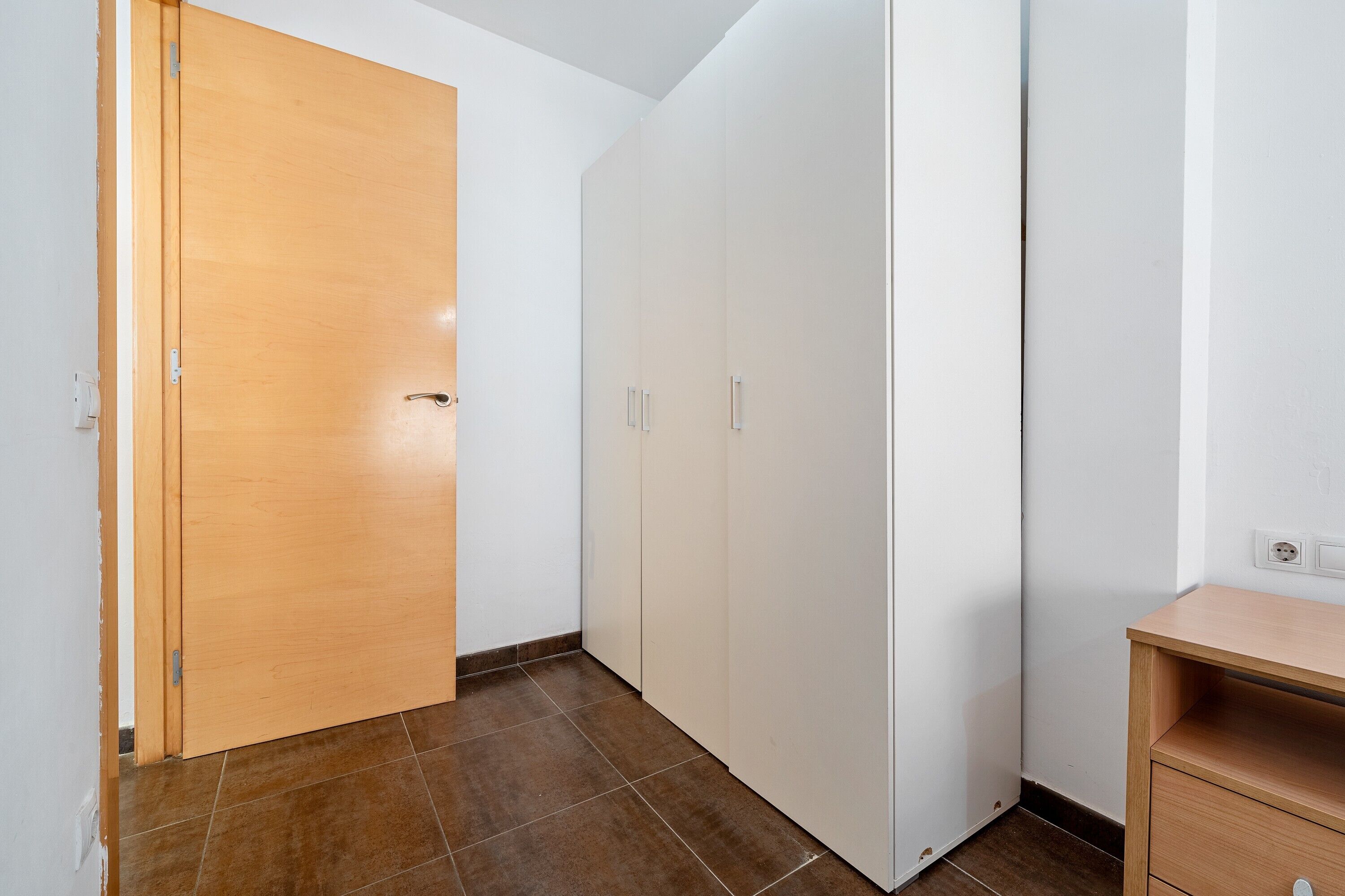 Une pièce avec une porte en bois, une armoire blanche et un bureau en bois.