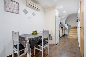 Une cuisine compacte comprenant un réfrigérateur, une table à manger avec des chaises et un escalier menant à un niveau supérieur.