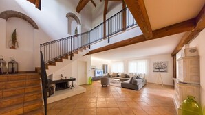Un vaste espace de vie agrémenté d’un escalier en bois, d’un ensemble de canapés et d’une cheminée.