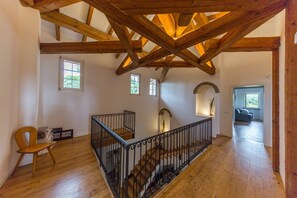 A spacious room with wooden beams, a staircase with black railings, and a view of another room through an open door. - Villa 'Minerva' with Lake View, Wi-Fi and Air Conditioning (Lazise)