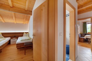 Træloft, en seng med bænk, et lille bord og en døråbning til et andet rum.