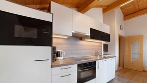 A modern kitchen with white cabinetry, stainless steel appliances, and a wooden ceiling.
