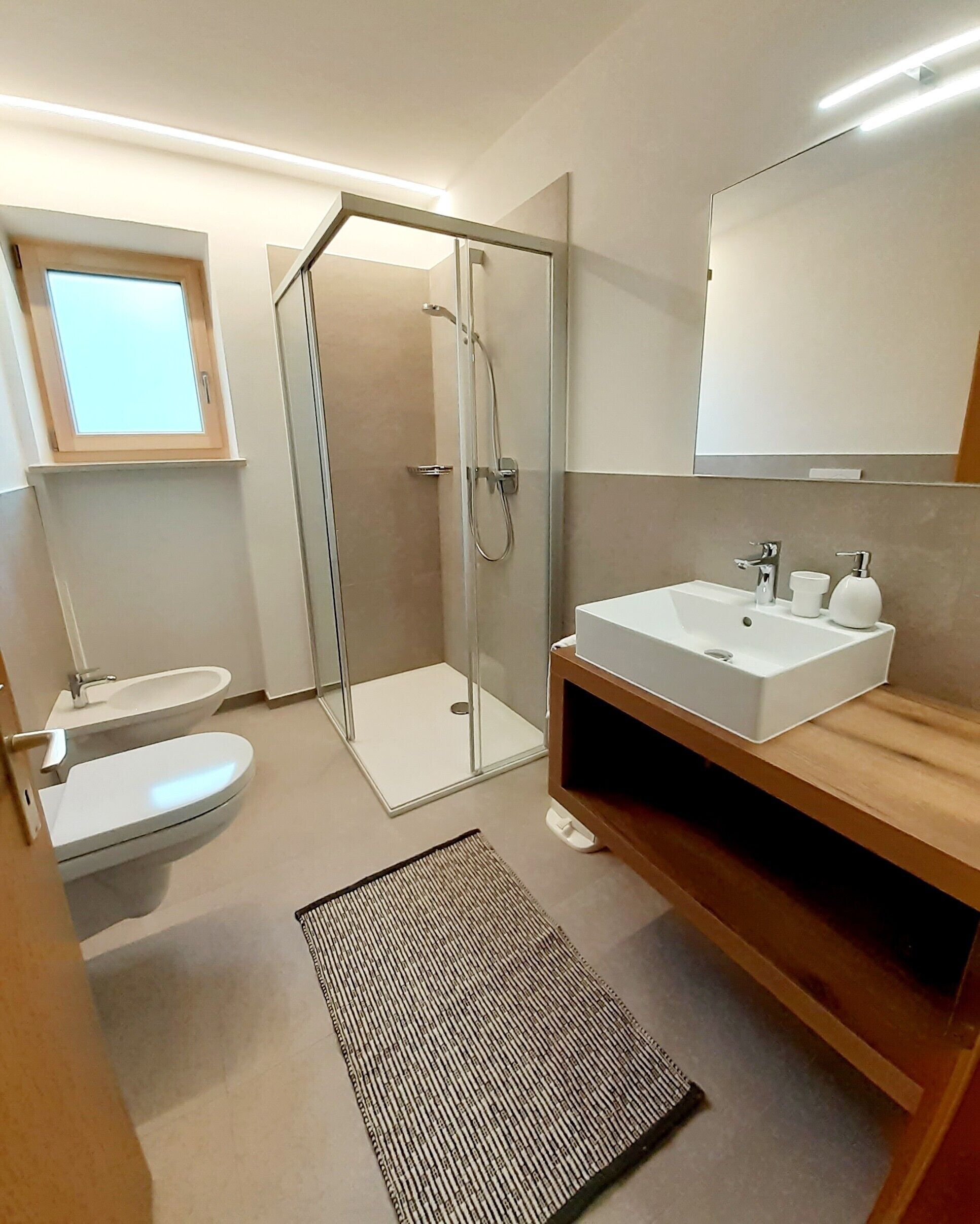 Une salle de bain moderne avec une douche à parois de verre, un lavabo blanc et des toilettes.