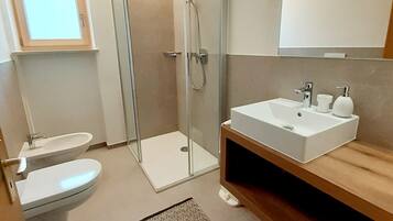 Une salle de bain moderne avec une douche à parois de verre, un lavabo blanc et des toilettes.