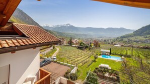 A residential area with a vineyard, a swimming pool, and a mountain backdrop. - Farmhouse 'Fröhlichhof Wohnung Panorama' with Mountain View, Shared Pool and Wi-Fi (Algund)