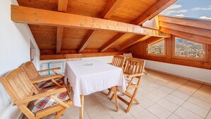 A wooden dining area with a table and chairs, a view through a window, and a sloped ceiling. - Farmhouse 'Fröhlichhof Wohnung Panorama' with Mountain View, Shared Pool and Wi-Fi (Algund)