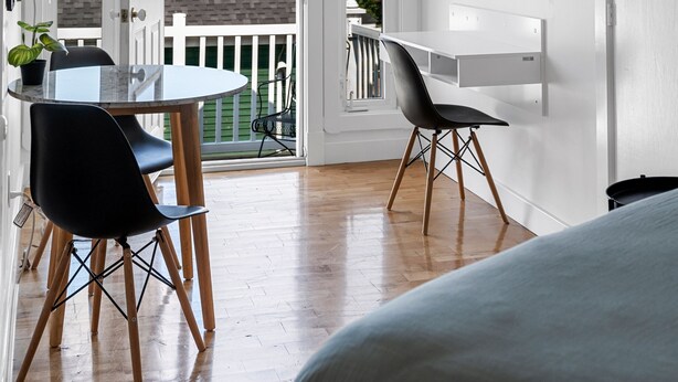 Un intérieur moderne et épuré, de couleur blanche, comprenant un coin repas, un balcon et une vue sur l’extérieur.