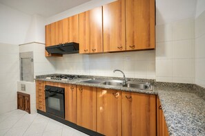 Una cocina con armarios de madera, un lavamanos de acero inoxidable, una estufa y un lavavajillas.