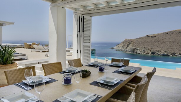 A dining area with a table set for four, overlooking a pool and a cliff. - Villa 'Blueros Luxury' with Sea View, Wi-Fi and Air Conditioning (Syros)