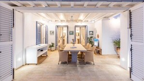A dining area with a central table, chairs, and a bench. - Villa 'Blueros Luxury' with Sea View, Wi-Fi and Air Conditioning (Syros)