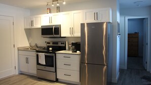 A modern kitchen with white cabinets, stainless steel appliances, and a wooden floor. - SHUSWAP GOLF AND LAKE ESCAPE
 (Blind Bay)