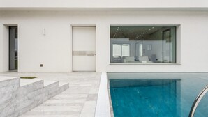 A modern building with a swimming pool, a staircase, and a large window.