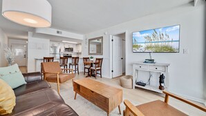 En moderne stue med en lædersofa, et træbord og et spiseområde med stole og bord.