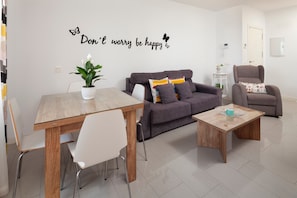 Una sala de estar moderna con una mesa de comedor, un sofá, una mesa de centro y una pared con una cita inspiradora.