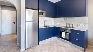 Une cuisine moderne avec des meubles de couleur bleu foncé, un réfrigérateur en acier inoxydable, un four et un four à micro-ondes.