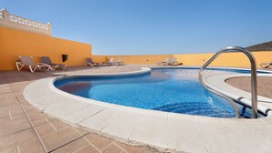 Une piscine avec des chaises longues et un ciel dégagé.