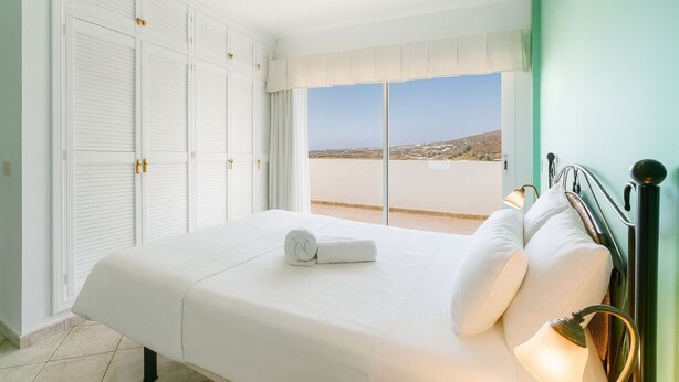 Une chambre à coucher avec un lit, une vue sur la plage et une armoire à portes.