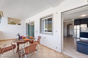 Un coin repas avec une table dressée pour quatre personnes, une cuisine équipée d’appareils modernes et une vue sur l’extérieur.