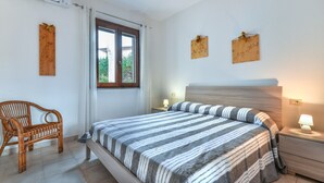 Une chambre à coucher comprenant un lit, une table de chevet, une chaise, une fenêtre et des éléments décoratifs fixés au mur.