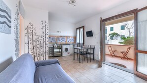 Une pièce comprenant un lit, une table à manger avec des chaises, un coin cuisine équipé d’appareils électroménagers et un balcon avec des chaises.