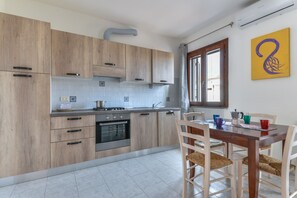 Une cuisine moderne avec des meubles de rangement en bois, une cuisinière et une table à manger avec des chaises.