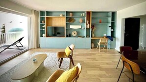 Un salon moderne équipé d’un téléviseur, de sièges et d’une bibliothèque intégrée.