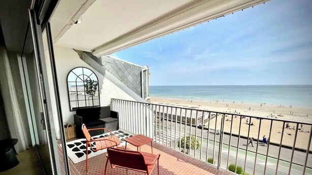 Un balcon avec vue sur la plage, un barbecue et des meubles pour se détendre en plein air.