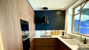 Une cuisine compacte avec des meubles en bois, un four encastré, un sol carrelé en marbre et une fenêtre offrant une vue agréable.