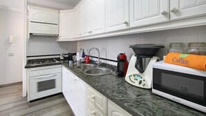 A kitchen with white cabinets, a stove, a sink, a coffee maker, and a microwave. - Vacation Apartment 'Las Teresitas Beach' with Mountain View, Balcony and Wi-Fi (San Andres)
