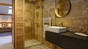 Un baño moderno con ducha de vidrio, tocador de madera y un espejo grande.