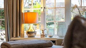 Une pièce chaleureuse avec une fenêtre, une lampe et des objets décoratifs sur une table.