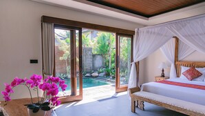 A bedroom with a bed, a bedside table with a vase of flowers, and a view of a swimming pool. - 2 Seasons : Villa Moon - Luxury with Private Pool (Ubud)