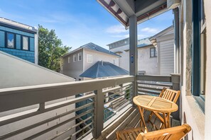 A balcony with a wooden table and chairs, overlooking neighboring houses.
