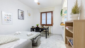Habitación pequeña con cama, escritorio, ventana y estantería.